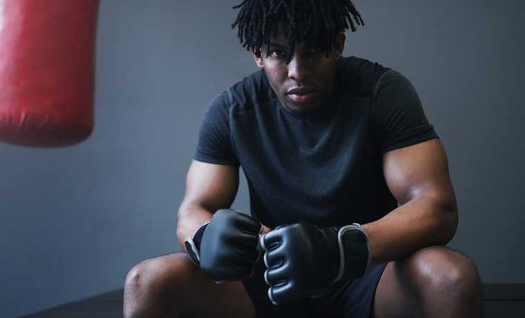 Shot of an athletic man sitting next to a boxing bag