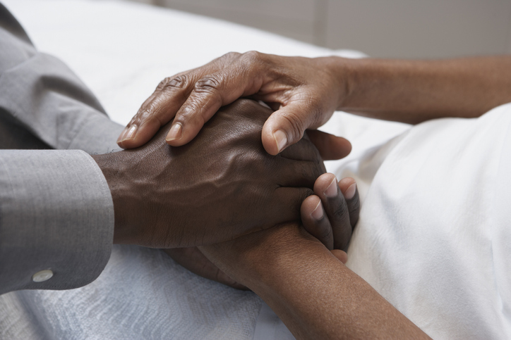 Close up of African man holding hands in hospital