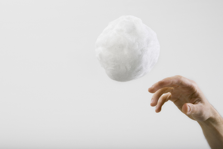 A human hand throwing a large cotton ball
