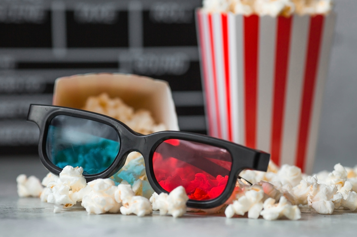 A banner for the film industry. A movie date. A movie camera, 3D glasses, popcorn in striped cups on a stylish concrete gray background. The premiere of the film.