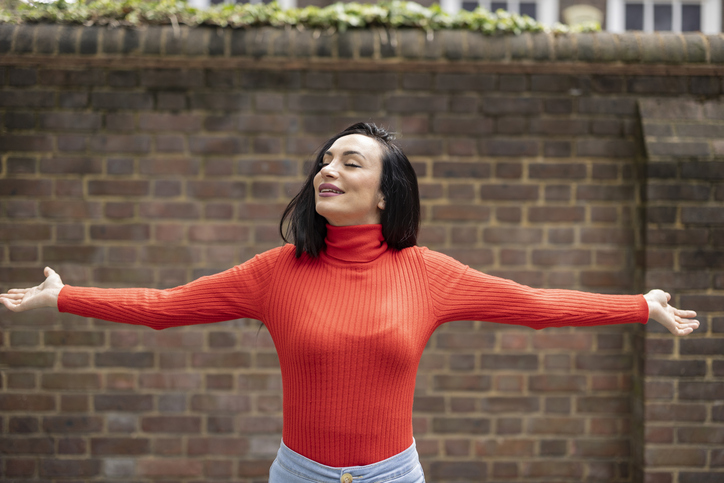Woman breathing fresh air with open arms in london