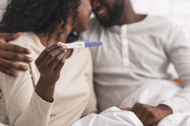 Happy african american couple showing pregnancy test with positive result