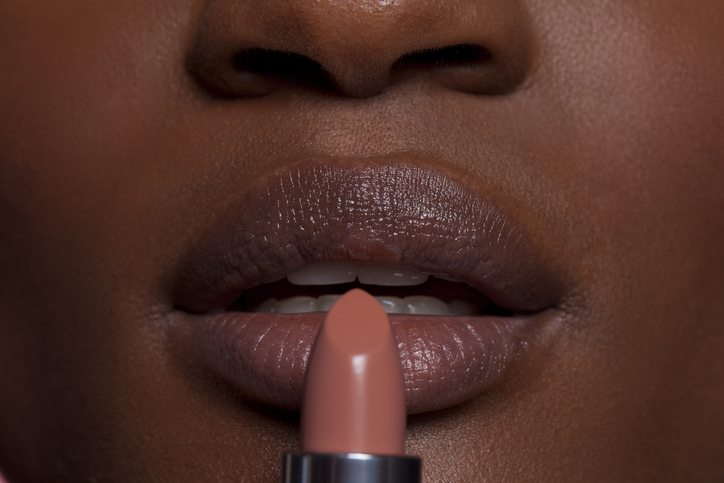 Young woman applying lipstick